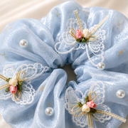 Close-up of blue organza scrunchie with pearls, lace butterflies and flowers