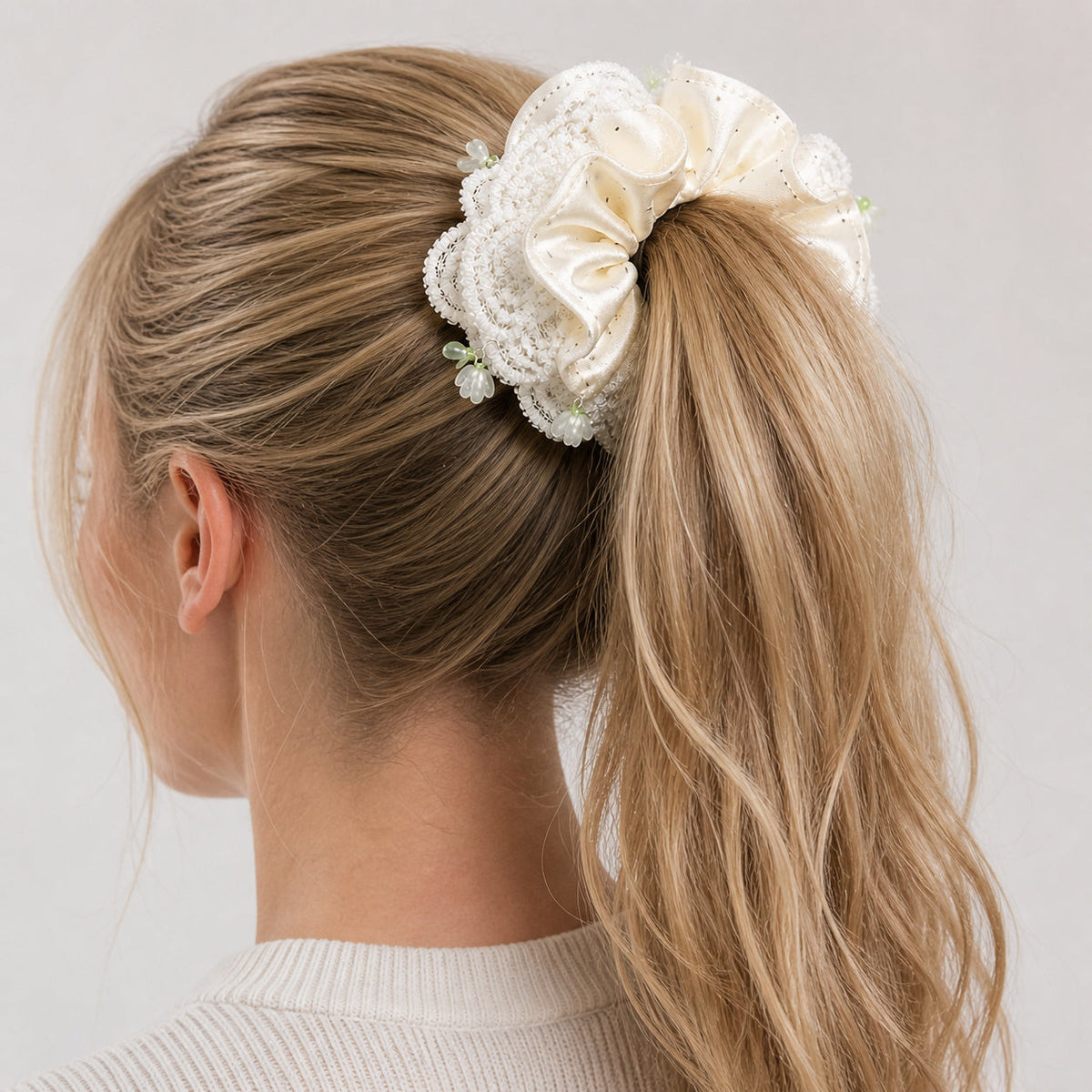 American woman wearing an ivory polka-dot satin and lace oversized scrunchie around a high ponytail
