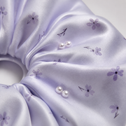 Close-up of pale lilac floral satin fabric and small pearl-like bead details