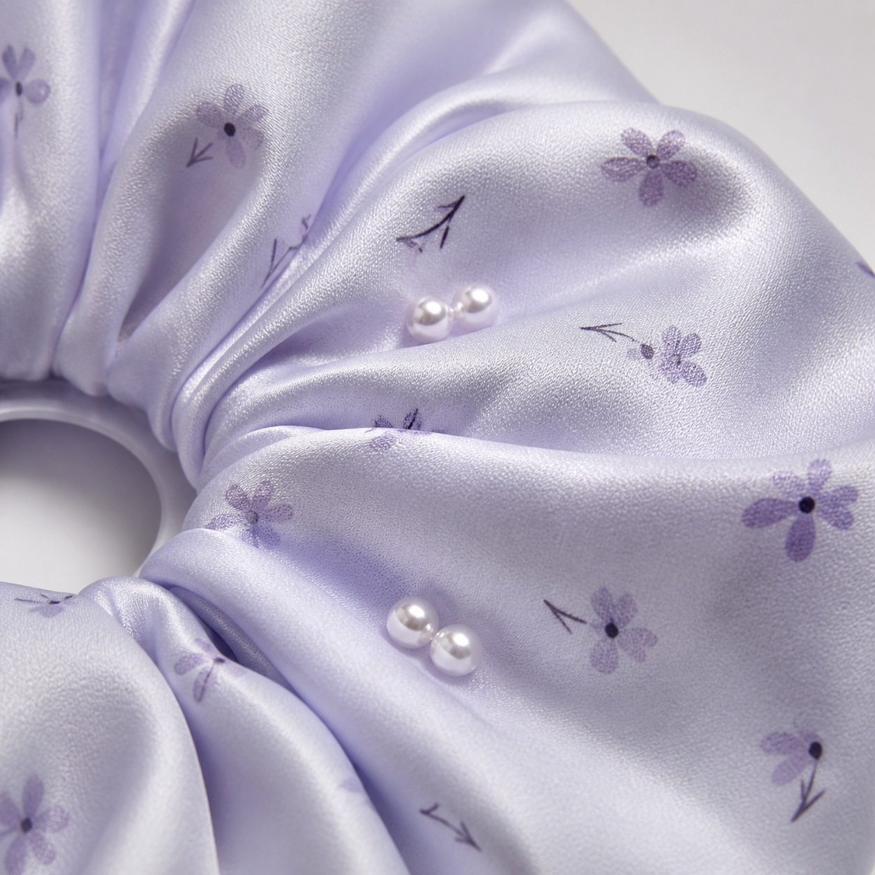 Close-up of pale lilac floral satin fabric and small pearl-like bead details