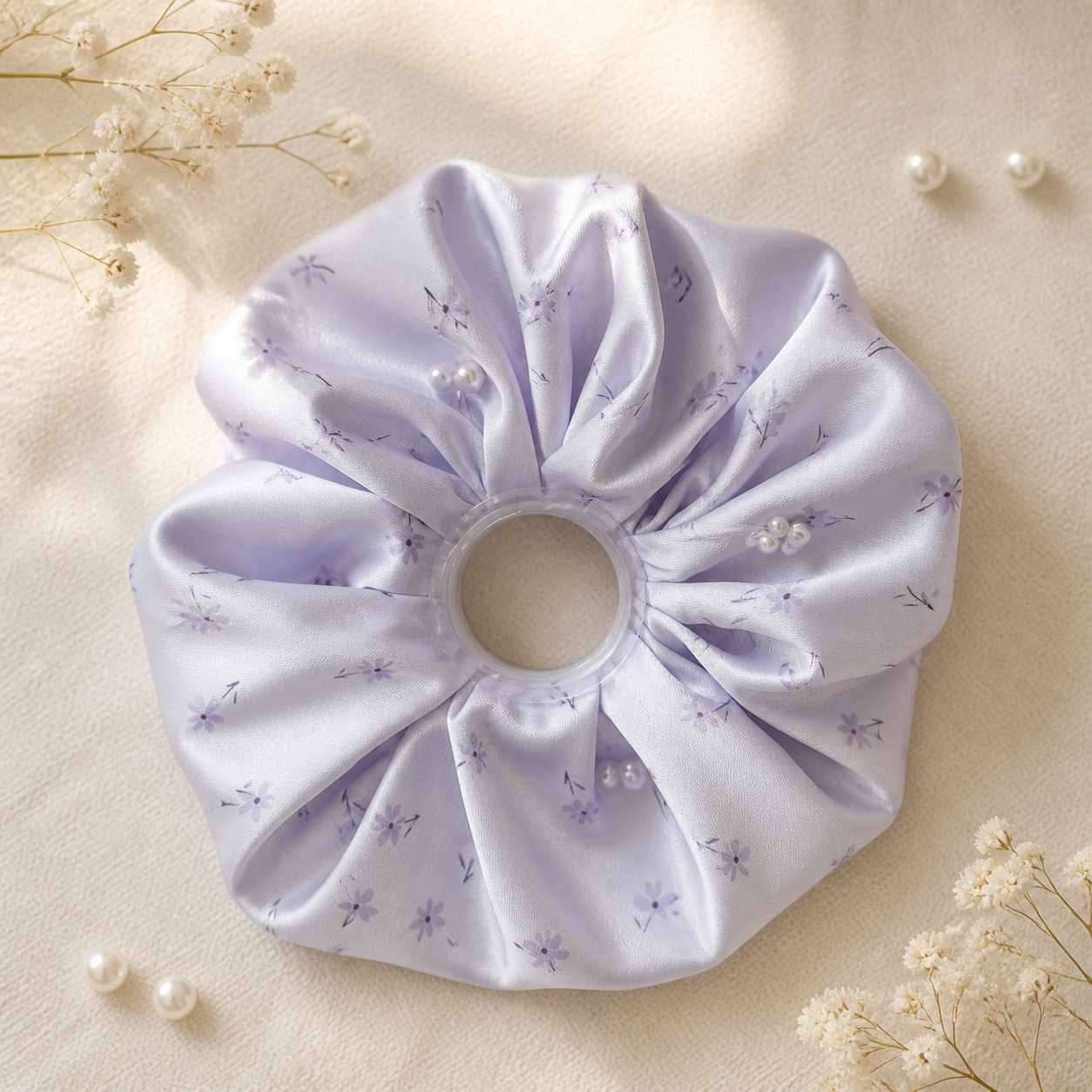 Pale lilac floral pearl satin oversized scrunchie styled on warm ivory linen