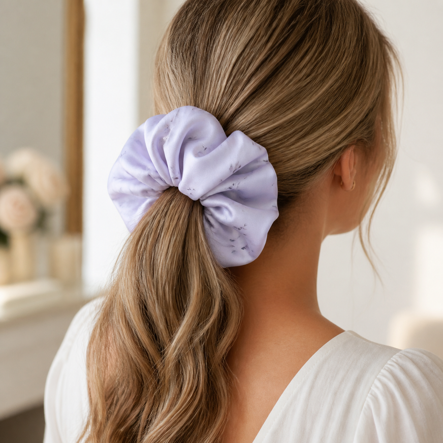 Woman wearing a pale lilac floral satin oversized scrunchie in a low ponytail