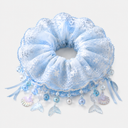 Ice blue mermaid lace scrunchie with pearl-like beads and ocean charms on a neutral gray-white studio background